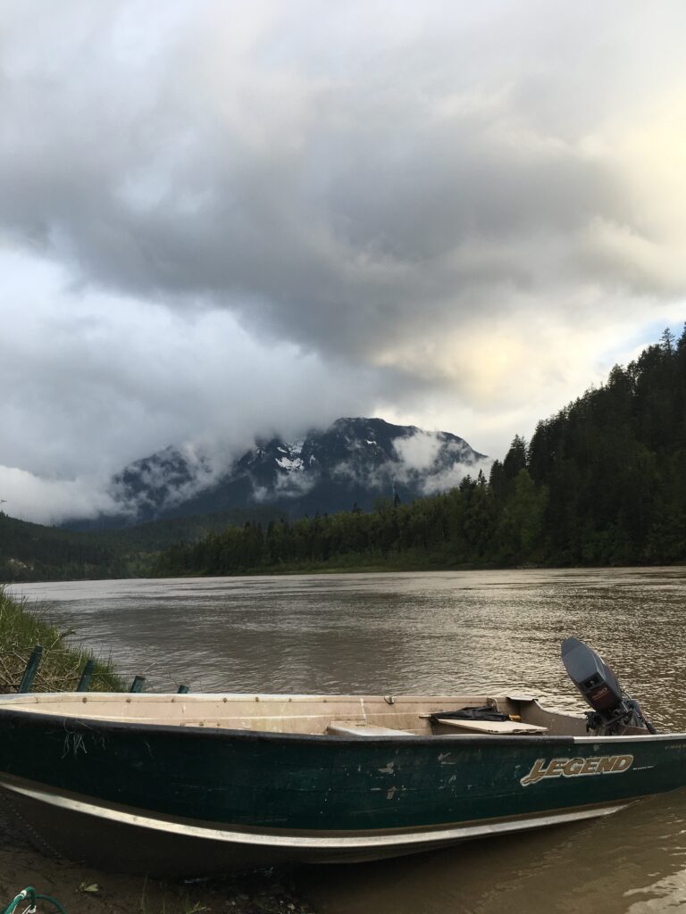 Boat pulled up on riverside mountain in background (Fraser River)