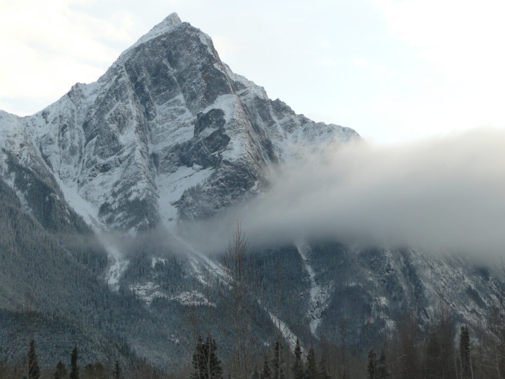 Thick band of cloud in front of tall snow-covered mountain peak (Hagwilget)